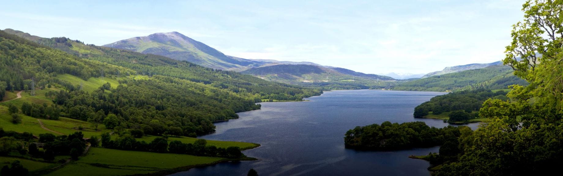 Lush, green valley with deep blue loch running through the middle
