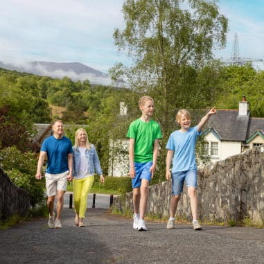 Family walking on a path away from a village