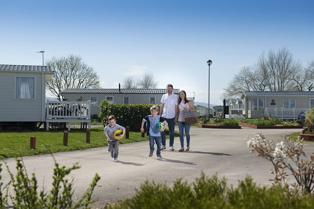 A family walking past holiday accommodation at Ty Mawr Holiday Park