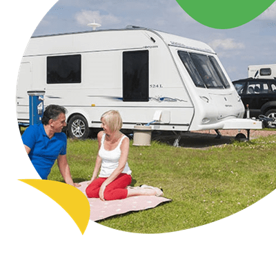 A family relaxing on the grass on the touring field at Ty Mawr Holiday Park