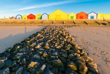 Sandy beach with a row of colourful beach huts