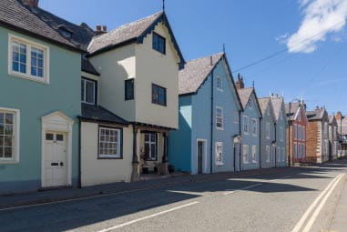 Row of pastel coloured houses with an odd white house nestled in between