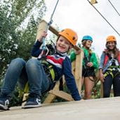 Child with helmet attached to a zip wire
