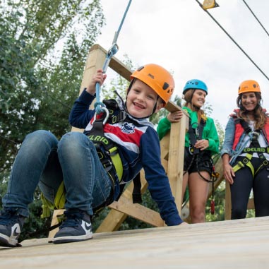 Child with helmet attached to a zip wire