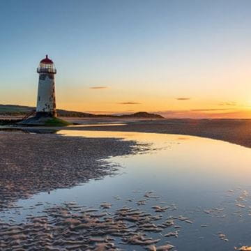 Pebble beach at sunset with a lighthouse in the distance