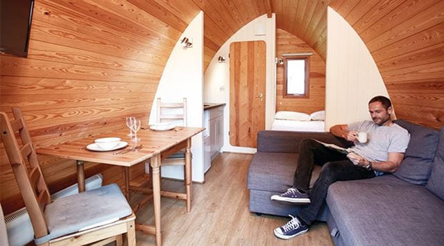 man relaxing on a sofa in a Glamping Mega Pod at Vauxhall