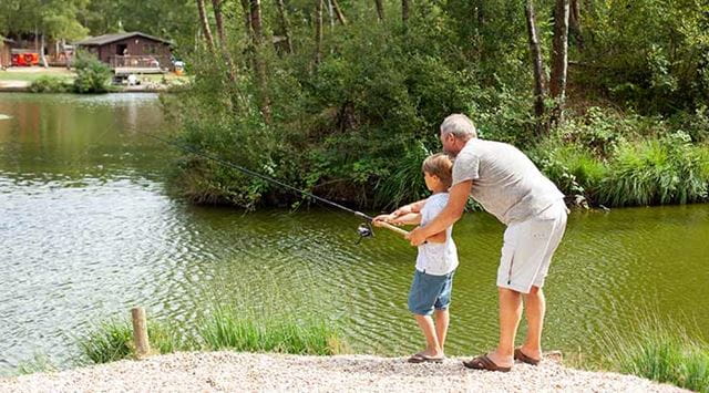 A man teaching a boy how to fish on the lake at Warmwell Holiday Park
