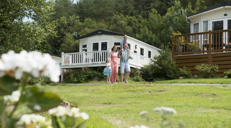 A family walking across the grass by the lodges at Wemyss Bay Holiday Park