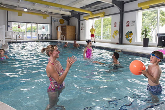 A family playing with a ball in the indoor swimming pool
