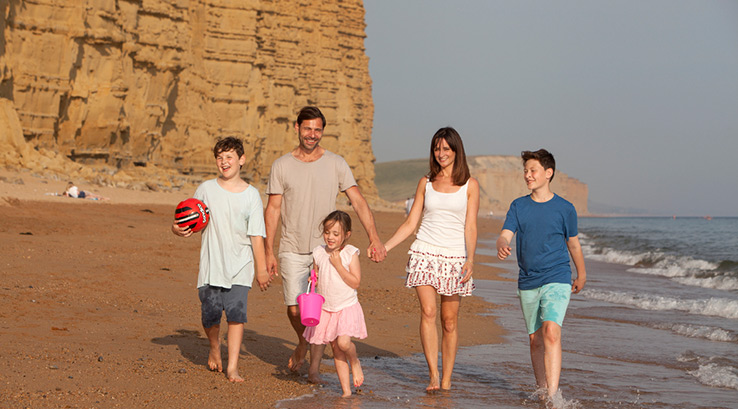 A family walking along the beach at West Bay