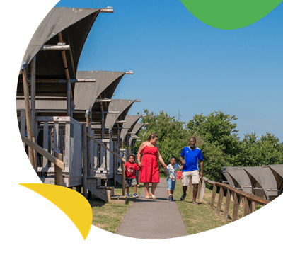 A family walking past glamping tents at West Bay Holiday Park