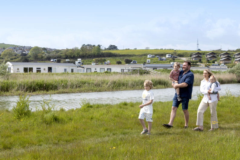 a family strolling along the side of a river