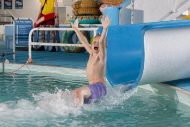 a child sliding down a waterslide into a pool