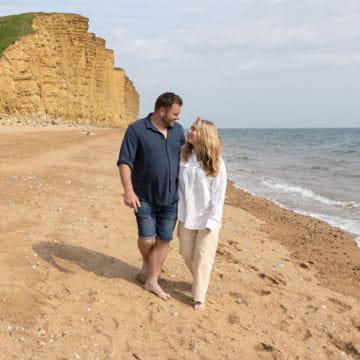 a couple walking along a beach 