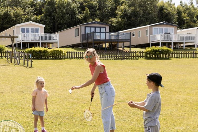 A row of caravans with a family playing badminton in front
