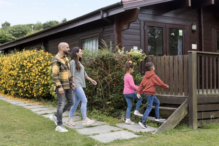 a family entering their wooden lodge caravan