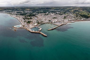 An aerial view over the town of Penzance with its harbour, and outdoor pool visible