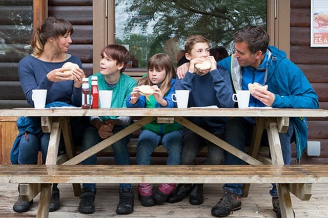 family sat at a picnic bench enjoying a meal at White Acres Holiday Park