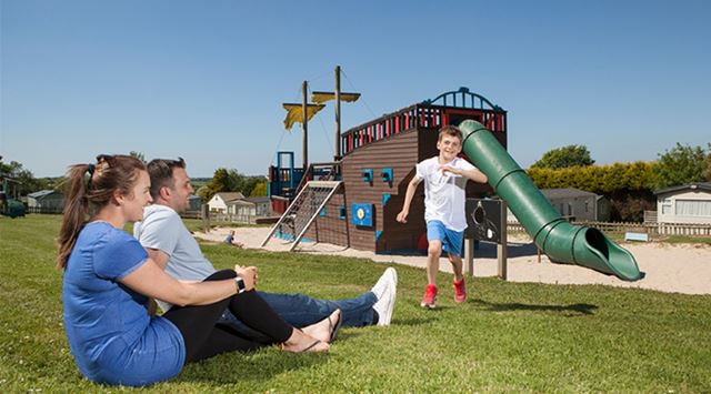 A family watching kids playing on the outdoor adventure playground at White Acres holiday Park