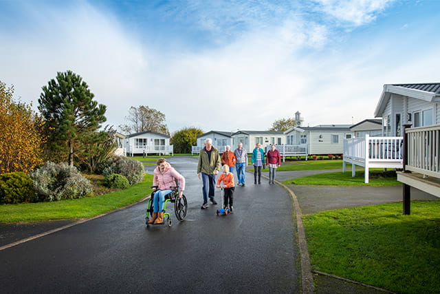 A family walking and a lady in a wheelchair and holiday caravans at Whitley Bay Holiday Park