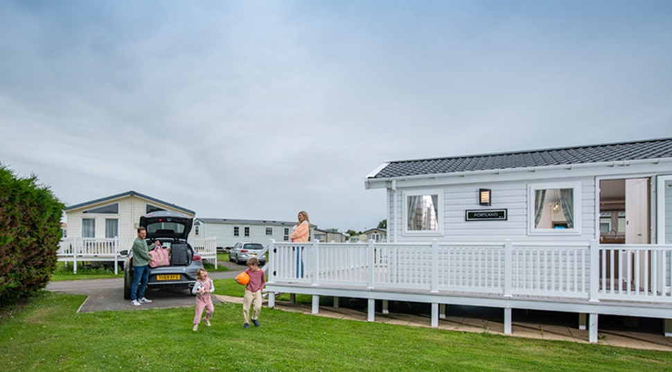 A family playing on the grass outside their caravan