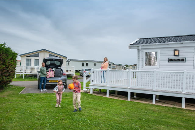 A family playing with a ball in front of their holiday caravan at Withernsea Holiday Park