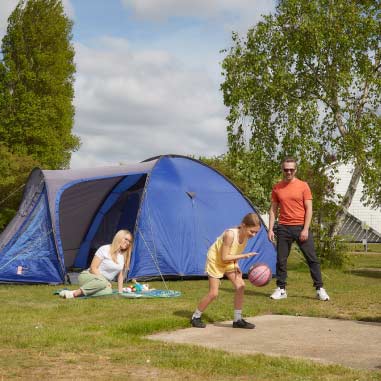 family playing football beside a tent