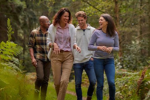 four adults walking together in woodland
