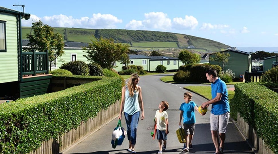 A family walking through Ruda Holiday Park in Devon on a sunny day