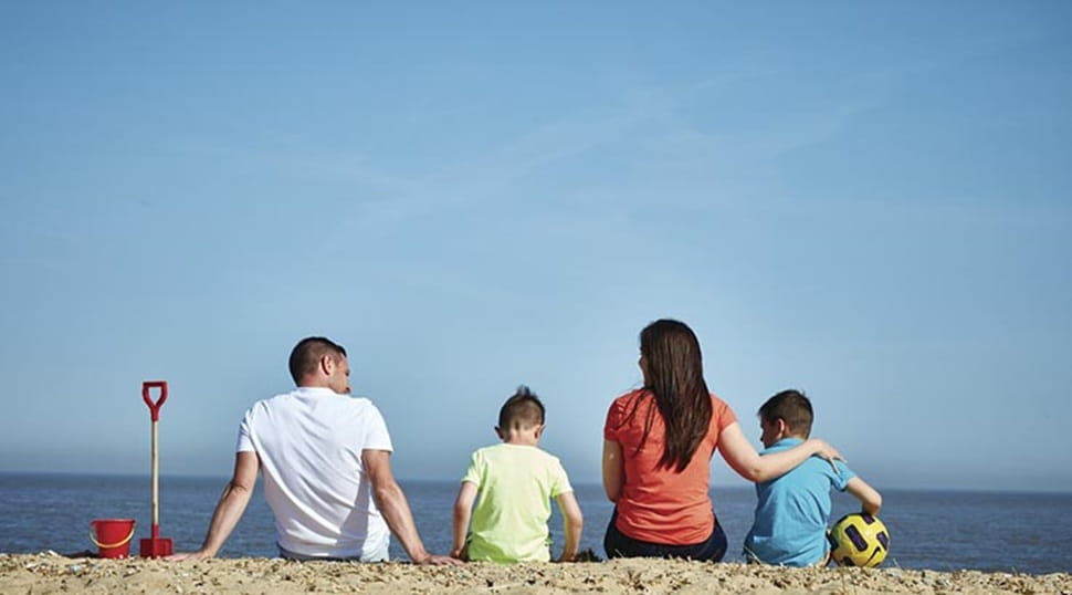 A family sitting on the sand and enjoying the sea view