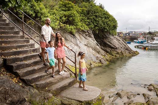 A family walking down some steps near a harbour in Cornwall