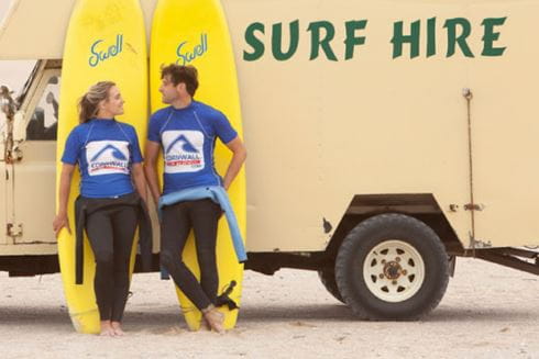 A couple leaning against surfboards in Cornwall