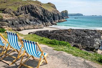 Deckchairs overlooking a beach in Cornwall on a summer's day