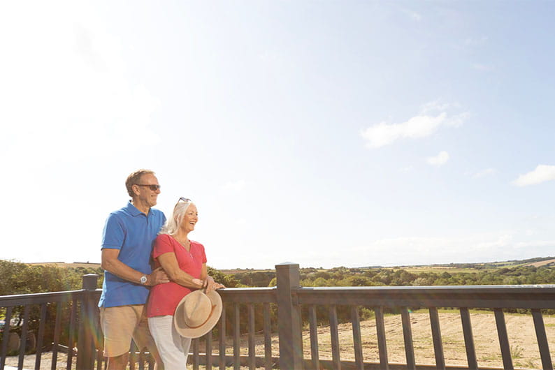 A couple standing on the veranda of their holiday home in Cornwall