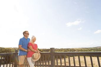 A couple standing on the veranda of their holiday home in Cornwall