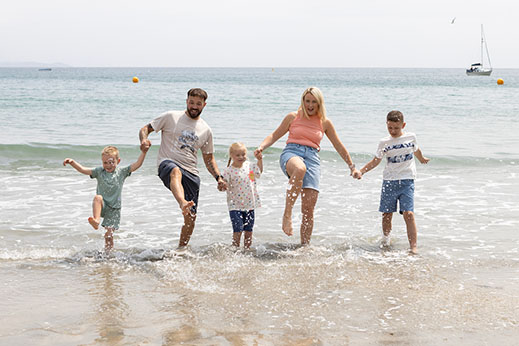 A family splashing in the waves at a Cornish beach