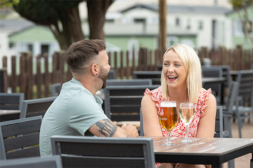 A couple enjoying a drink at a Parkdean Resorts holiday park in Cornwall