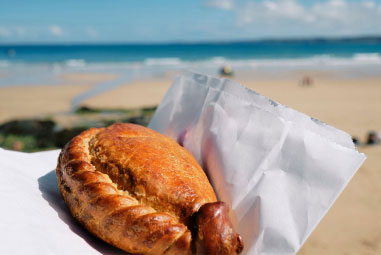A cornish pasty with the beach visible behind