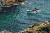 A fishing boat heading into a cove in Cornwall