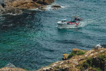 A fishing boat heading into a cove in Cornwall
