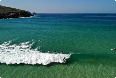 Surfers lining up to catch waves at Fistral Beach in Cornwall