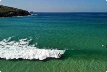 Surfers lining up to catch waves at Fistral Beach in Cornwall