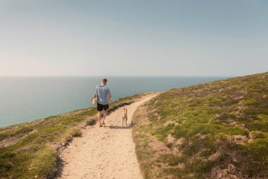 Man walking dog along the coast
