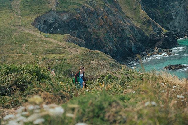 A couple of friends taking photos of the views on a walk along the Cornwall coast