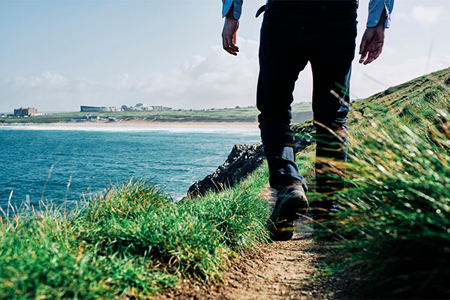 A walker on Pentire Headland in Newquay, overlooking Fistral Beach
