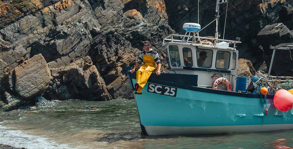 A Cornish fisherman sitting on a boat in a cove
