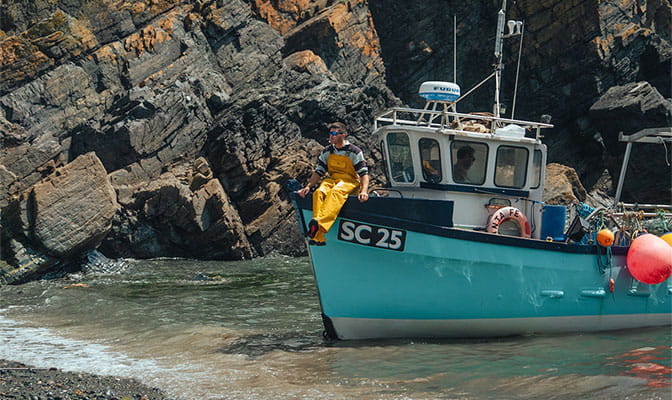 A Cornish fisherman sitting on a boat in a cove