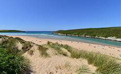 The Gannel Estuary flowing out to sea alongside Crantock Beach in Cornwall