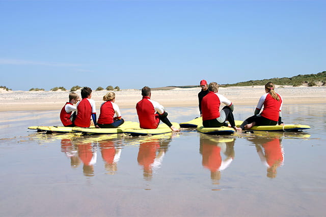 A group of tourists taking a surfing lesson in Cornwall