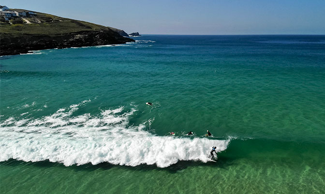 Surfers sitting in the bay at Fistral Beach waiting to catch a wave